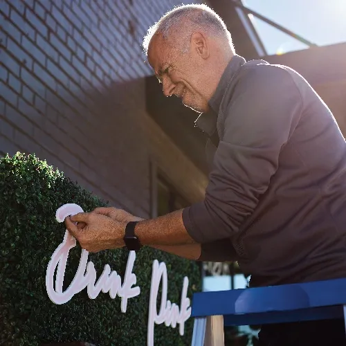 Man installs signage on faux greenery