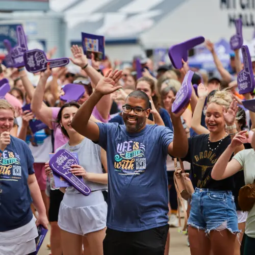 A crowd dances and laughs, all with Best Buddies foam fingers on their hands
