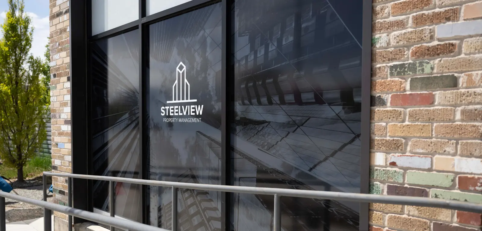 A large window outside of a building with a graphic showing skyscrapers and the Steelview logo