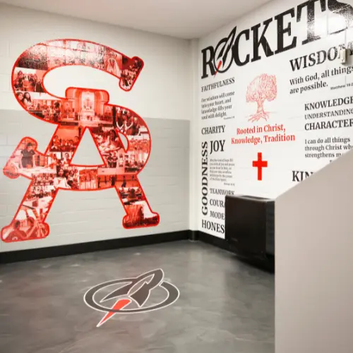 Wall with a large logo with photos inside of it and another wall with motivational phrases