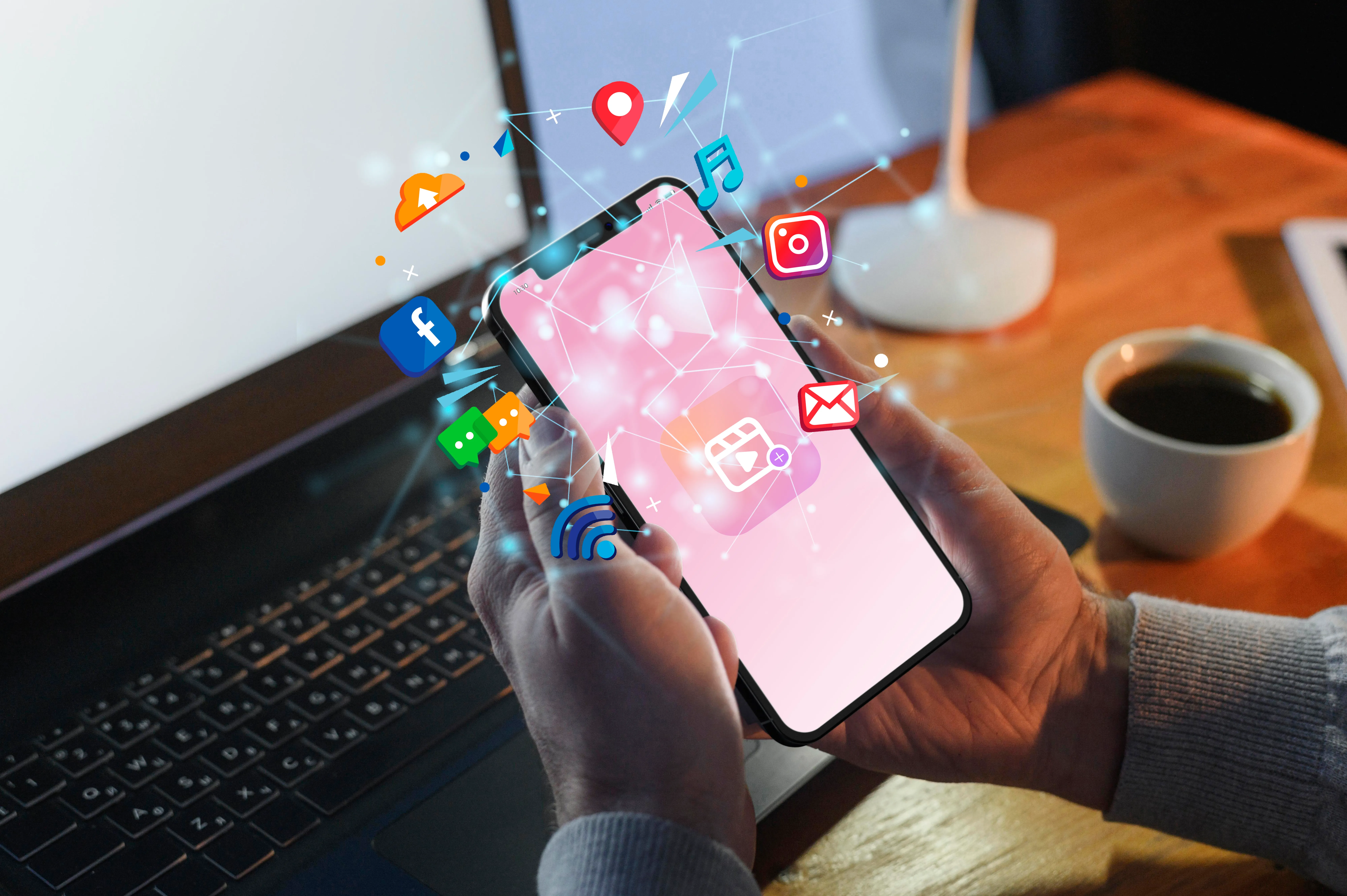 Hands holding a smartphone with various social media graphics around