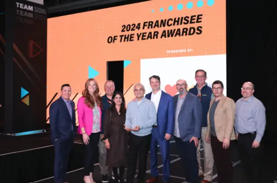Image of the AlphaGraphics team picture behind Mehul Patel as he accepts an award
